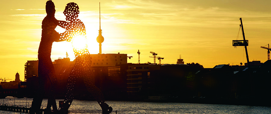 Kran-ballett foran solnedgangen i Berlin. En av dem har en helt spesiell last