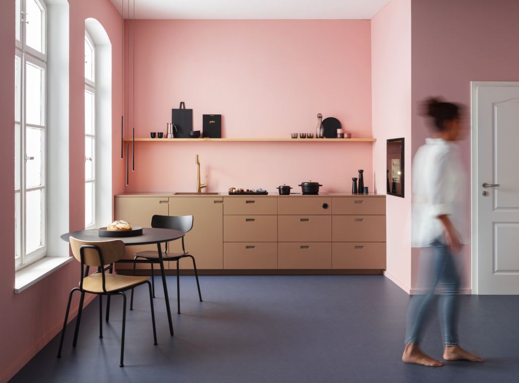 Bilde av et lite, moderne rosa kjøkken og en dame som er uskarp - illustrerer BORA S Pure er laget til de minste kjøkken og gir overraskende mange muligheter.