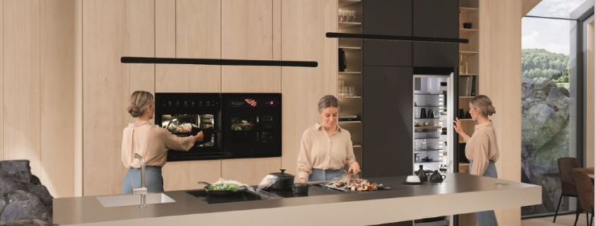 Bilde av et kjøkken med flere hvitevarer fra BORA og en dame som åpner BORA Cool - kjøleskap, kombiskap og fryseskap fra BORA